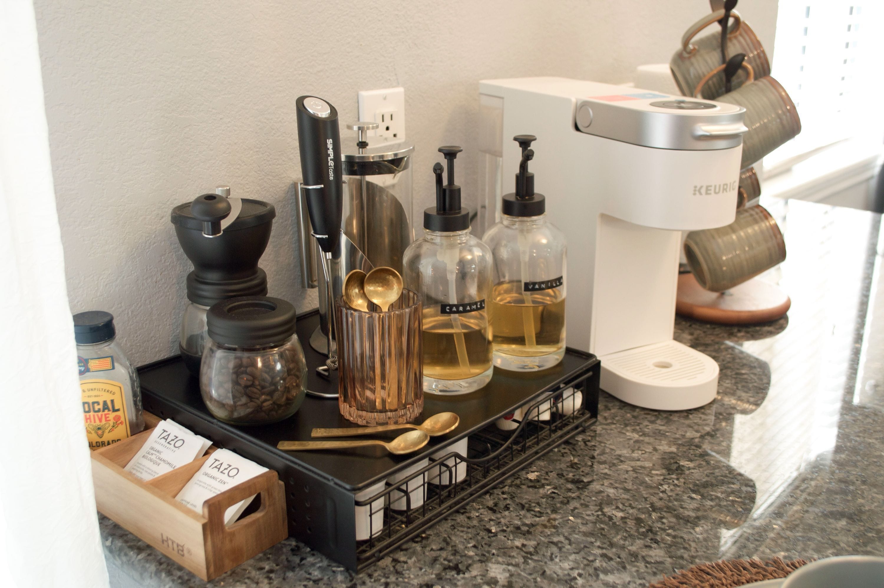 Un comptoir de cuisine avec du matériel pour préparer le café, des bocaux remplis de grains de café et une machine à café.