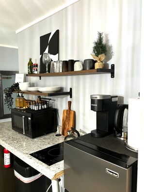 Eine moderne Küche mit integriertem Mikrowellenherd, Kaffeemaschine und Schneidebrett aus Holz.