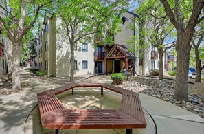 A courtyard with a wooden bench, surrounded by trees and buildings with balconies. - Cozy Private Studio Near Denver - Prime Location (Englewood)