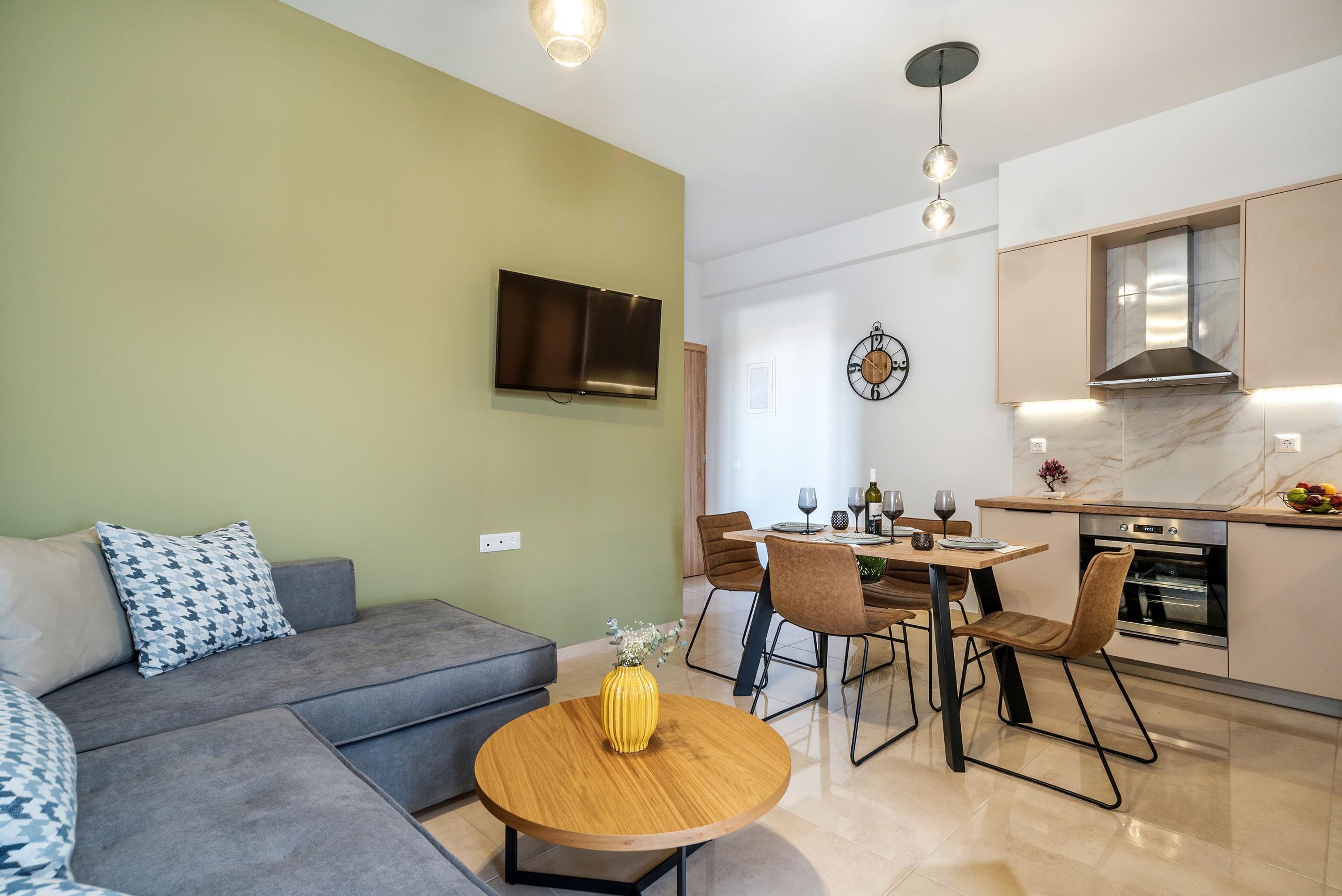 Ein modernes Wohnzimmer mit einem grauen Sofa, einem Holztisch und einem an der Wand befestigten Fernseher.