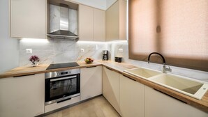 A modern kitchen with a built-in oven, a stainless steel range hood, and a double sink.