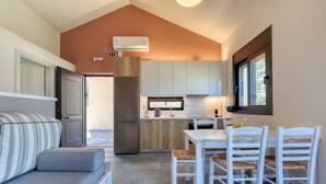 A compact kitchen with a built-in oven, a refrigerator, and a microwave. There is a dining table with four chairs. - Lemonia Suites in Ikaria (Ikaria)