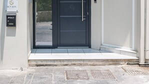 A modern building entrance with a double door, a post box, and a sign indicating the address 21-25. - Senaon Urban Living City Center (Heraklion)