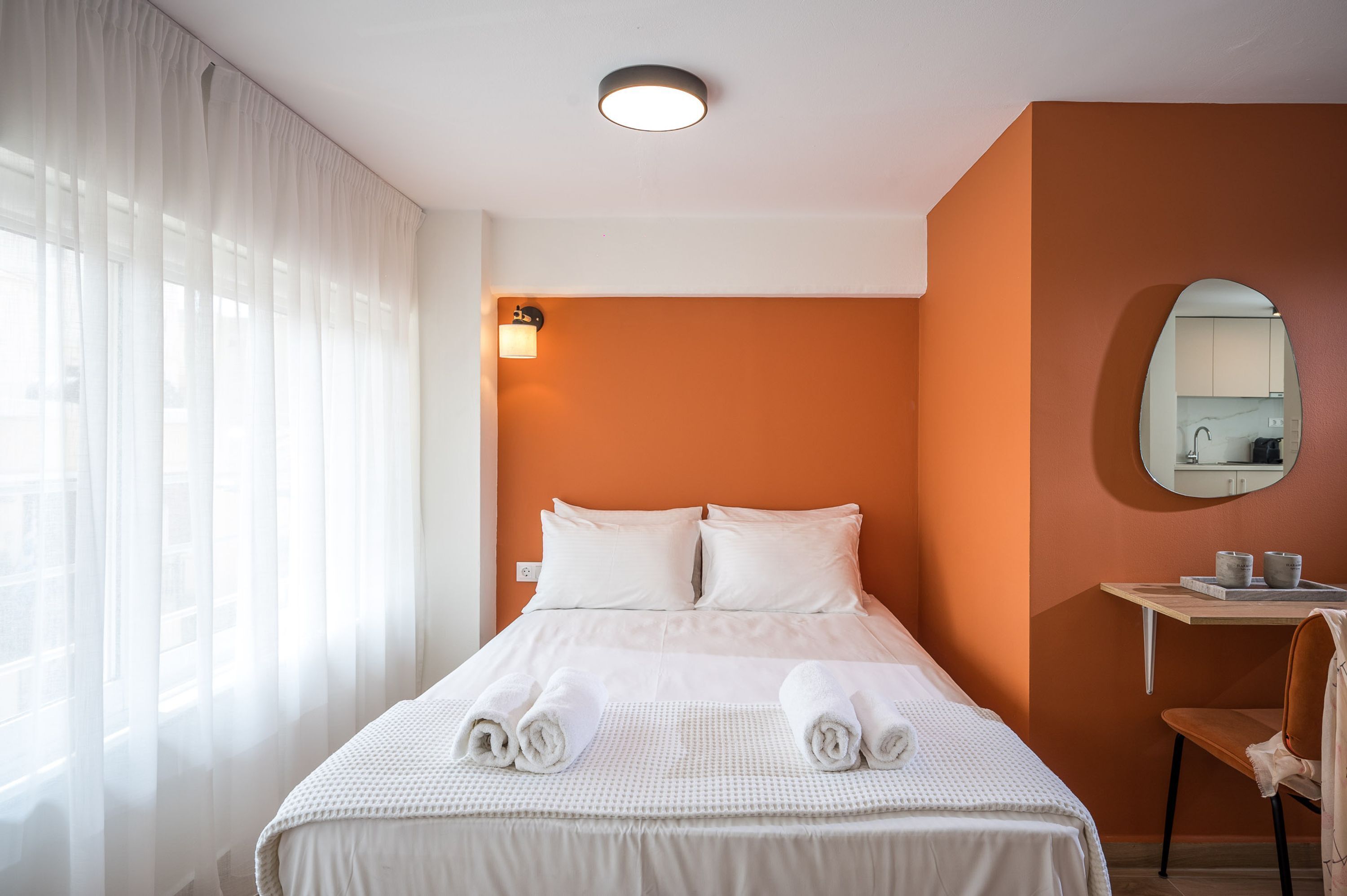 Une chambre d’hôtel avec un lit, un bureau, une chaise et un miroir.