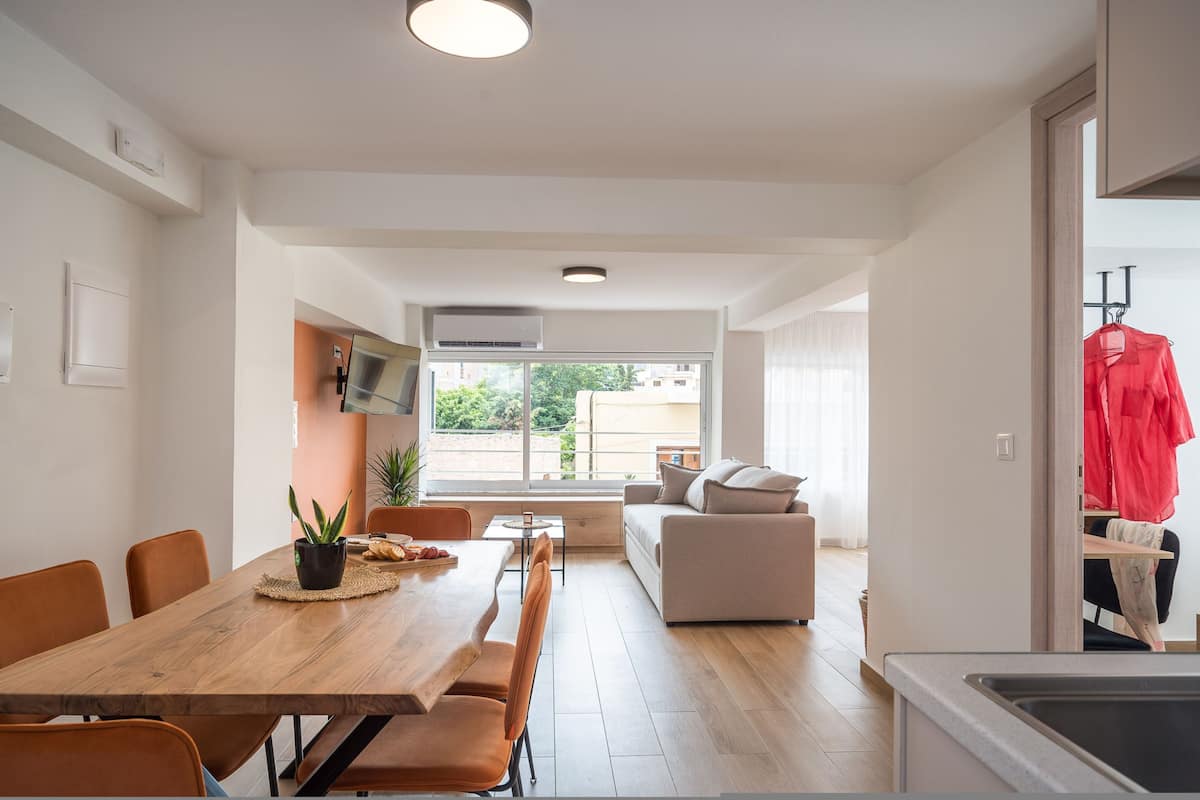 Eine moderne Küche mit einem Holztisch und Stühlen, einem eingebauten Backofen und einem großen Fenster.