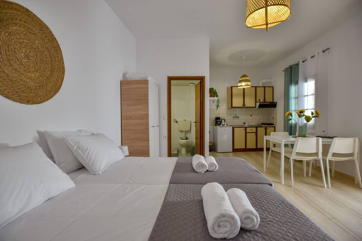 A hotel room with a bed, a desk, and a kitchenette.