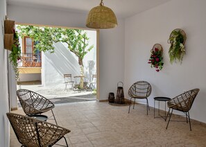 A room with wicker chairs, a small table, and hanging plants.