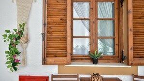 A wooden window with shutters, a macrame wall hanging, and a potted plant on the windowsill. - Eva Studios & Apartments by Cretan Houses (Malevizi)