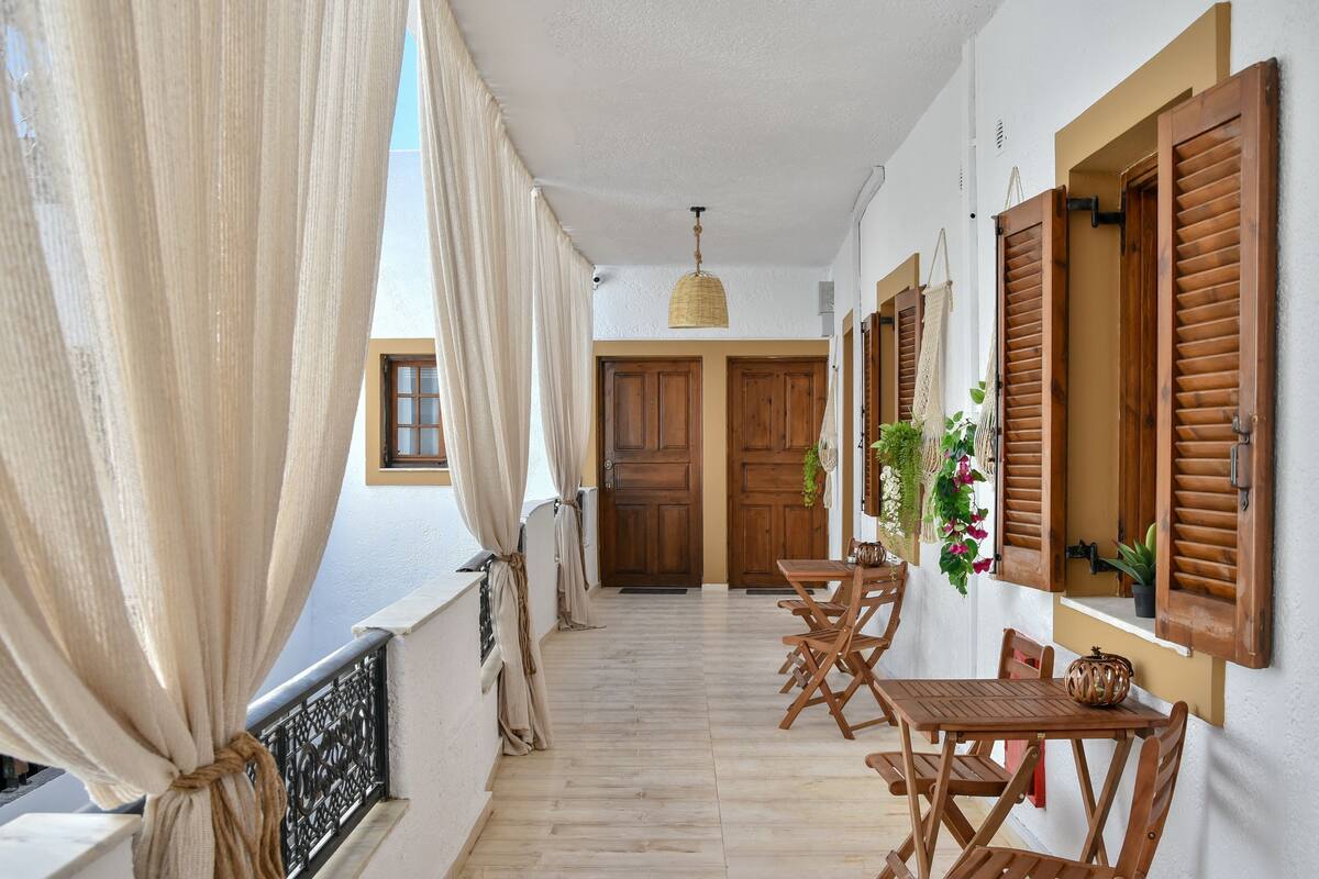 A corridor with wooden doors, a dining area with wooden furniture, and a hanging light fixture.