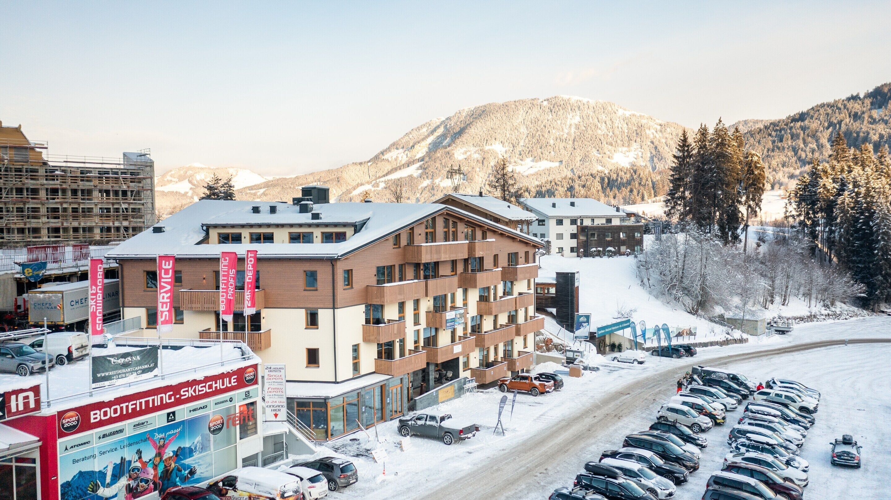 Un hôtel à plusieurs étages offrant des services d’entretien et d’ajustement des skis et des chaussures de ski, situé au cœur d’un paysage enneigé et entouré de montagnes.