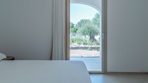 Une chambre à coucher avec un lit, une fenêtre avec des rideaux et une vue sur la verdure.