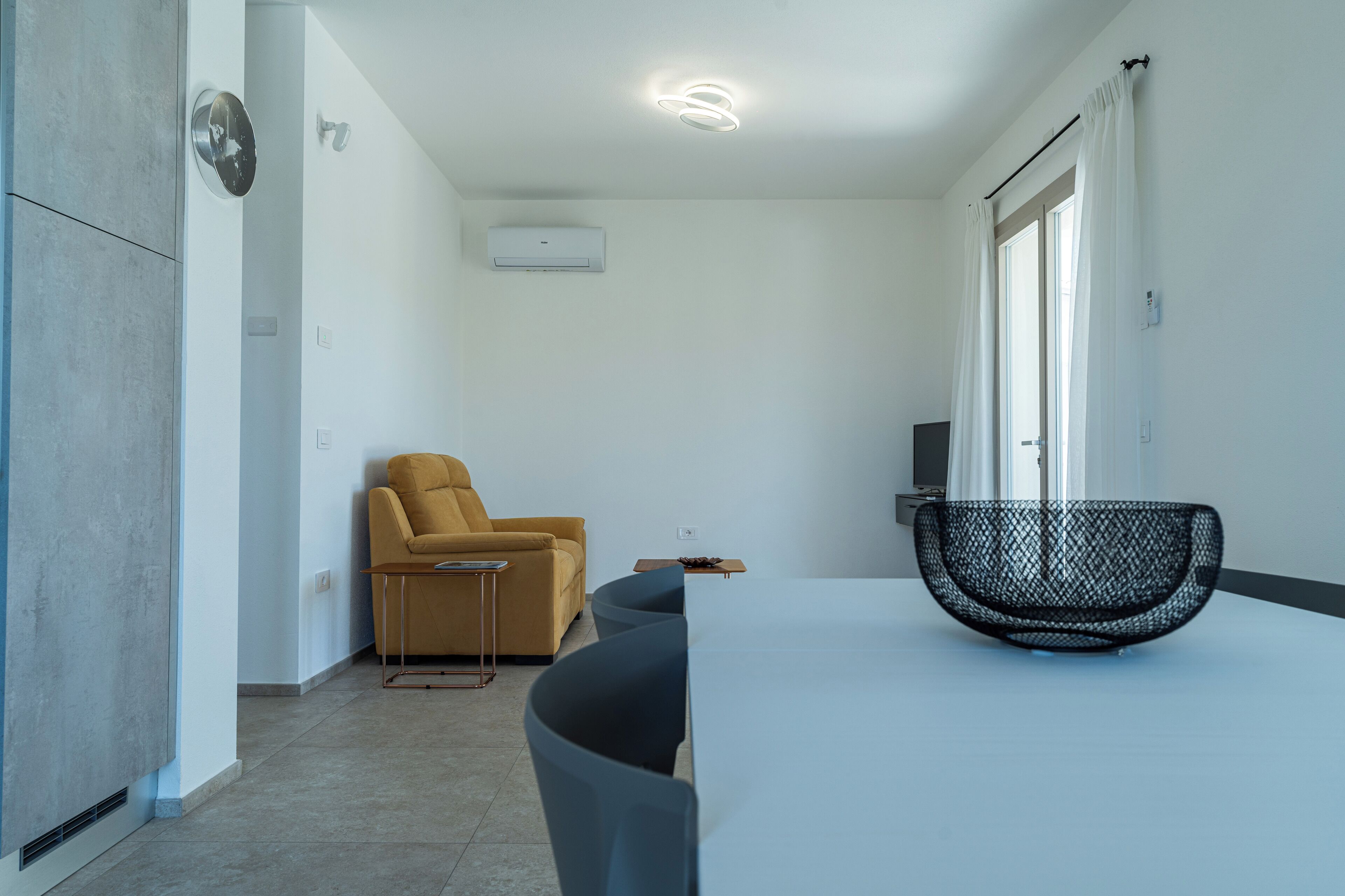 A modern room with a sofa, a dining table, and a black chair.