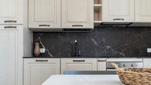 Une cuisine moderne avec des meubles de couleur bois clair, un pare-feu en marbre noir et une cuisinière en acier inoxydable.