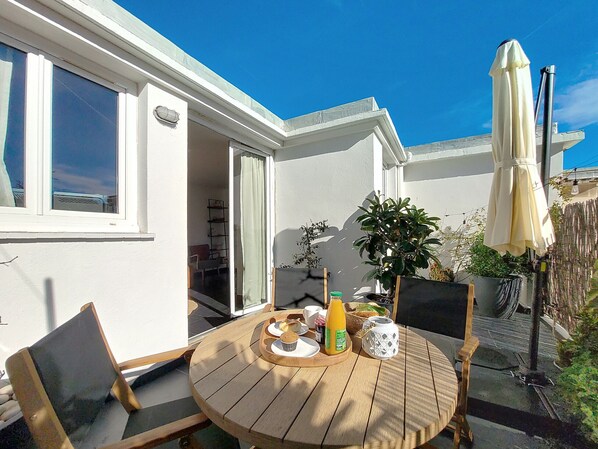 A patio with a round wooden table, chairs, and a white umbrella. - N&J - TERRASSE DU SUD - Central - Near Beach (Niza)