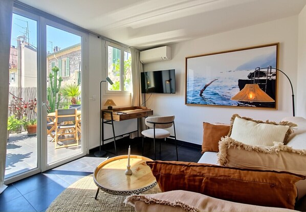 A modern living room with a sofa, a round coffee table, and a TV mounted on the wall.