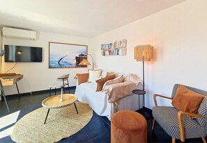 A modern living room with a sofa, armchairs, a coffee table, a TV, and a bookshelf.