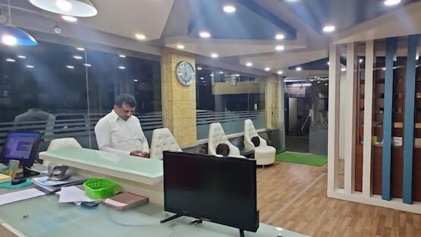 A reception area with a desk, computer, and seating area. - Joy Lux Stay (Anekal)