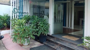 A hotel entrance with a glass door, a sign reading "Dreamz", and potted plants outside. - Joy Lux Stay (Anekal)