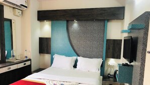 A hotel room with a bed, bedside tables, a TV, and a mirror. - Joy Lux Stay (Anekal)