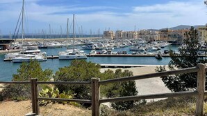 Un puerto deportivo con numerosas embarcaciones amarradas, rodeado de edificios y un cielo despejado.