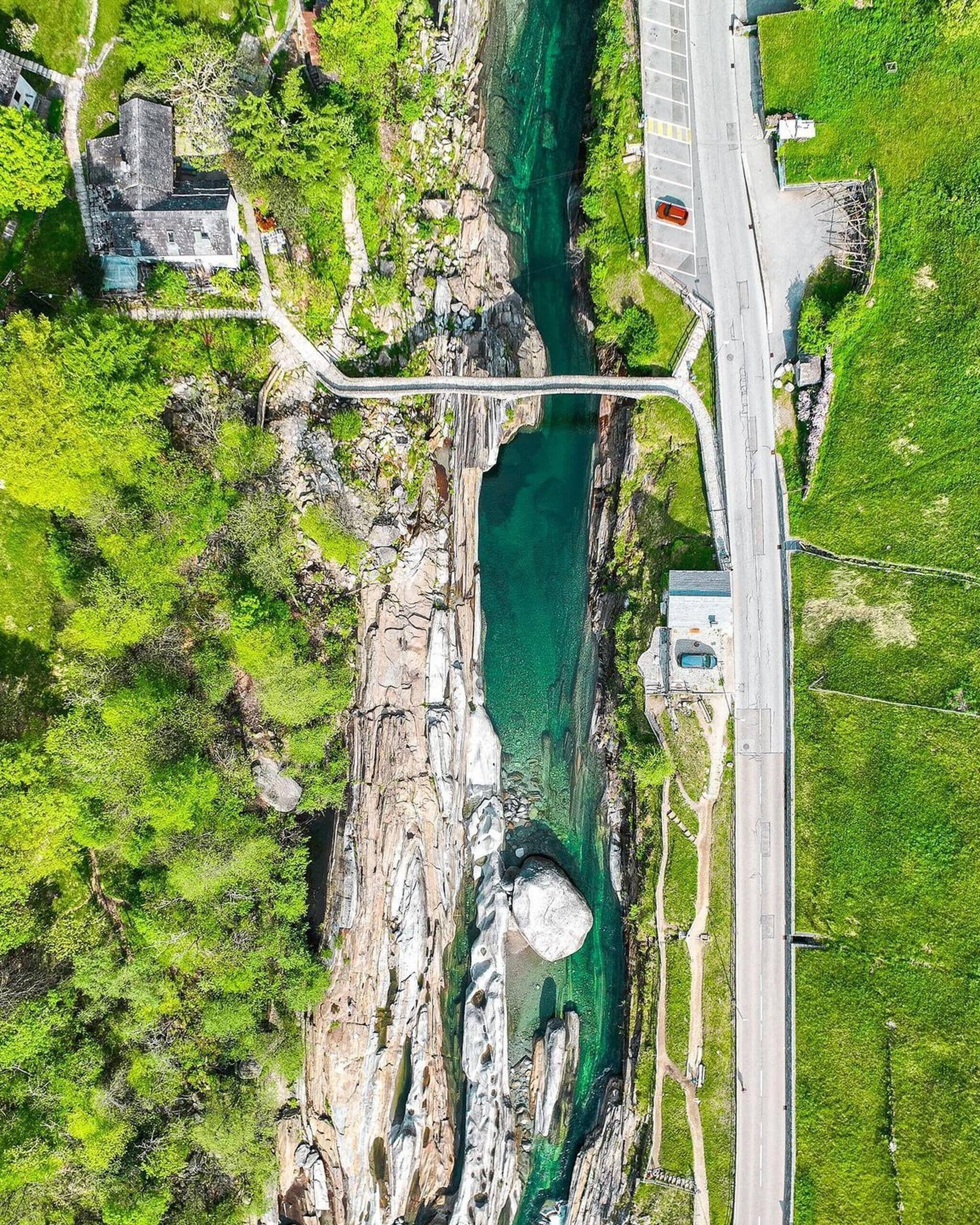 An aerial view of a coastal area with a bridge, a road, and a rocky cliff with a clear water channel.