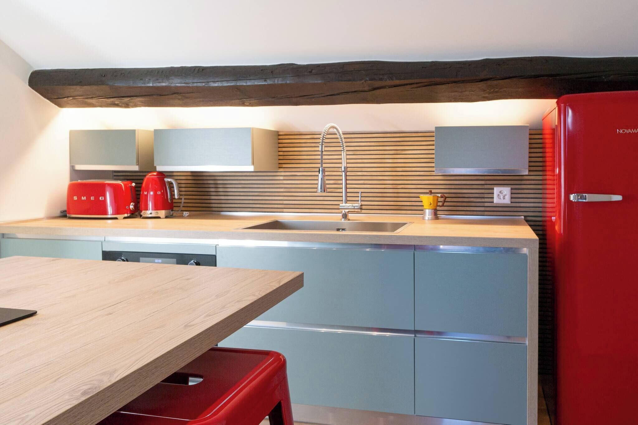 Een keuken met een houten tafel, een rode koelkast en een gootsteen.