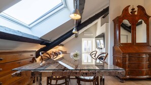 A dining area with a glass-top table, wooden chairs, a chandelier, and a wooden cabinet with a mirror. - Luxury Suite Sunrise in Losone (Losone)