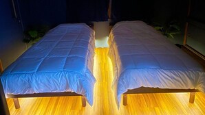 Dos camas con ropa de cama blanca, cabeceros de madera y suelo de madera.