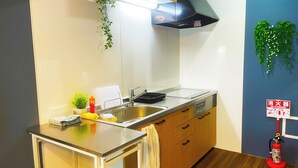 Una cocina moderna con un lavamanos de acero inoxidable, armarios de madera, horno empotrado y un extintor de incendios colgado en la pared.