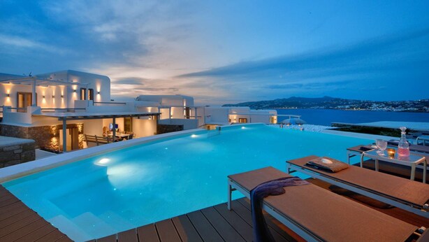 Ein modernes Hotel mit großem Infinity-Pool, Sitzgelegenheiten im Freien und Meerblick.