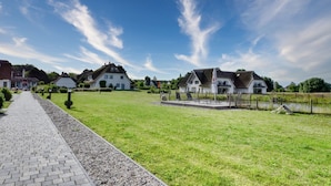 Un quartier résidentiel doté d’une allée pavée, de pelouses verdoyantes et de maisons aux toits inclinés.