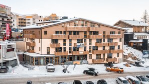Un hôtel à plusieurs étages doté de balcons, une station de ski en arrière-plan et de la neige au sol.