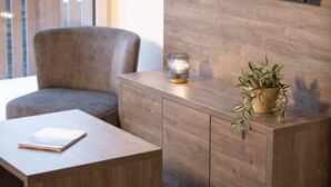 Un soggiorno moderno con un mobiletto in legno, un televisore a parete, una poltrona grigia e un tavolino con un libro.
