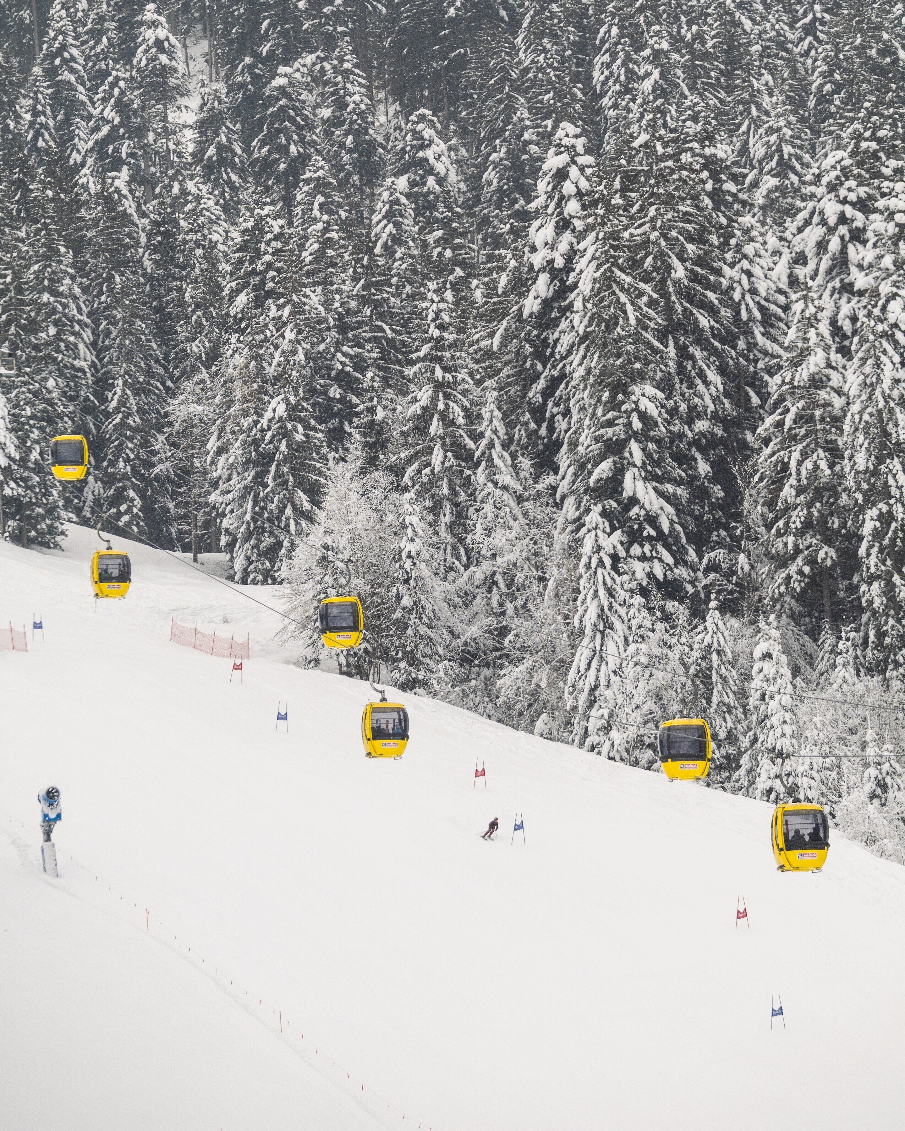 A snowy ski slope with yellow ski lifts and red and blue flags marking the course.