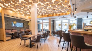 Un interior de restaurante moderno con suelo de madera, varias zonas de estar y un diseño de techo único.