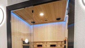Una sauna con interior de madera, puerta de vidrio y sistema de ventilación.