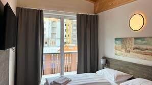 Una habitación de hotel con una cama, un cuadro en la pared y una ventana con cortinas.