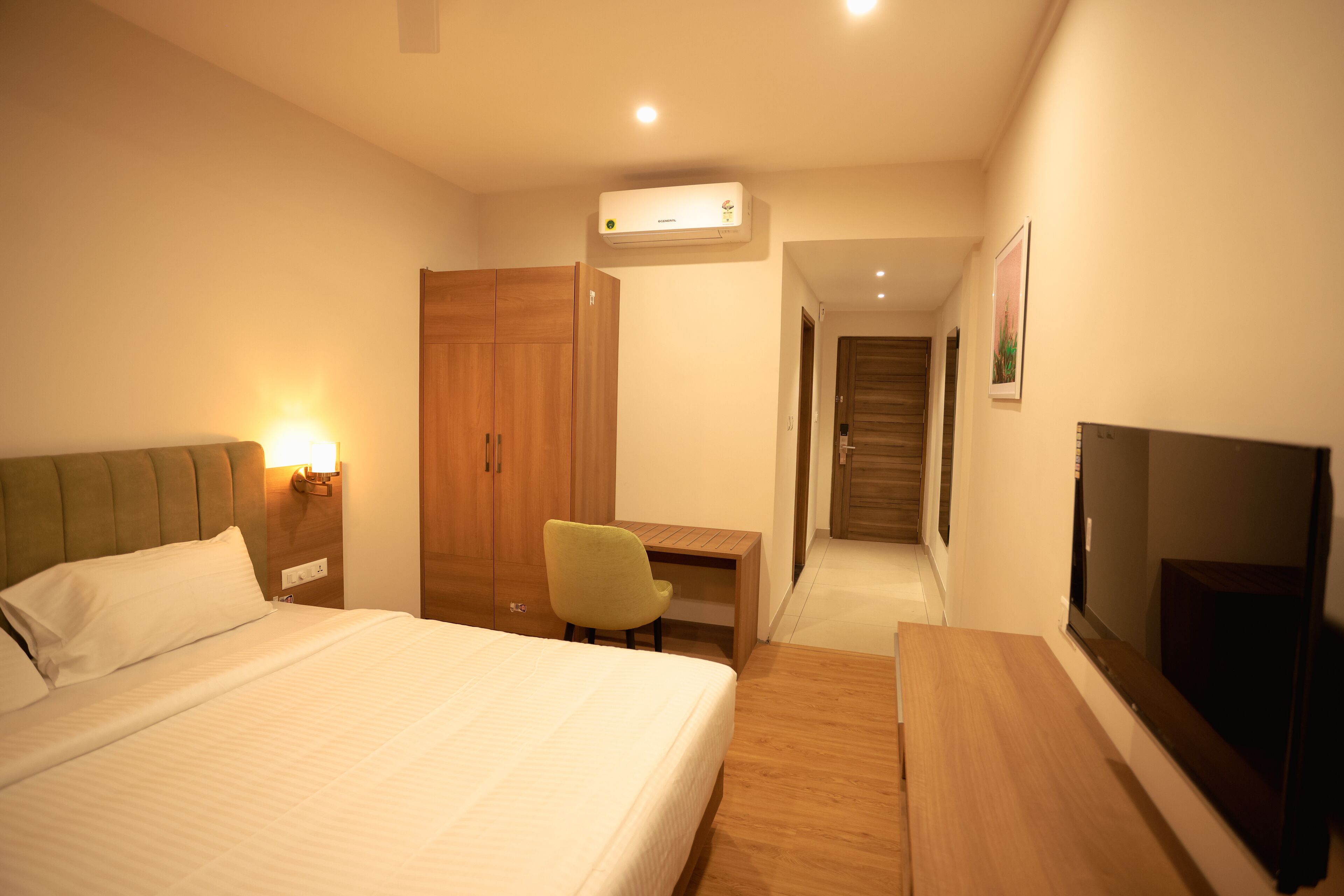 Habitación de hotel con cama, escritorio, silla, aire acondicionado y televisor.