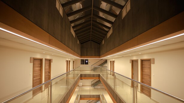 A spacious interior with a central atrium, glass railings, and wooden accents. - Hilux Courtyard (Palakkad)