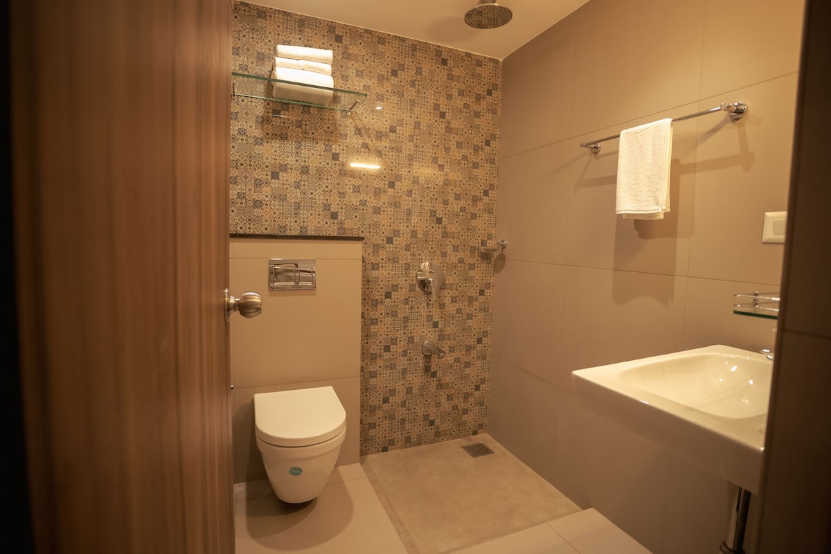 A bathroom with a toilet, shower, and sink.
