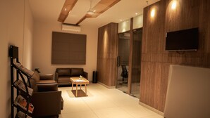A modern living room with a sofa, a coffee table, and a bookshelf. - Hilux Courtyard (Palakkad)