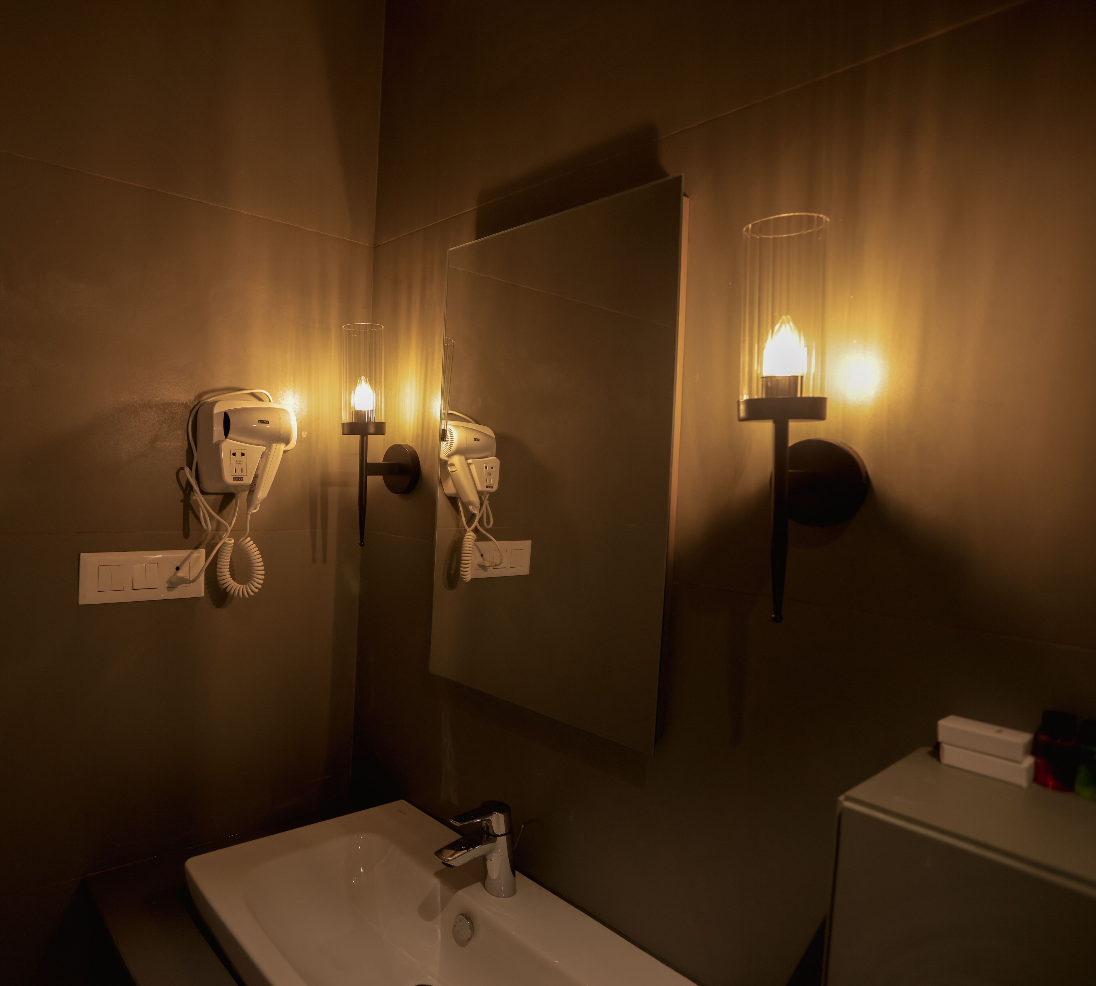 A bathroom with a white sink, a hairdryer, and a mirror.