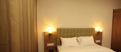 Una habitación de hotel con cama, mesitas de noche y lámparas de pared.