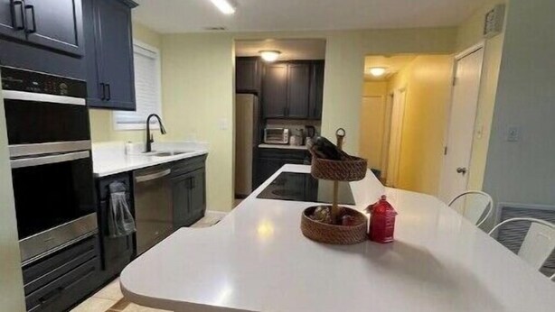 A compact kitchen with dark cabinets, a white countertop, and a dining area with a white table and chairs. - Vacation getaway (Morehead City)