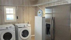 A laundry room with two front-loading washing machines, a stainless steel refrigerator, and a ceiling fan. - Vacation getaway (Morehead City)