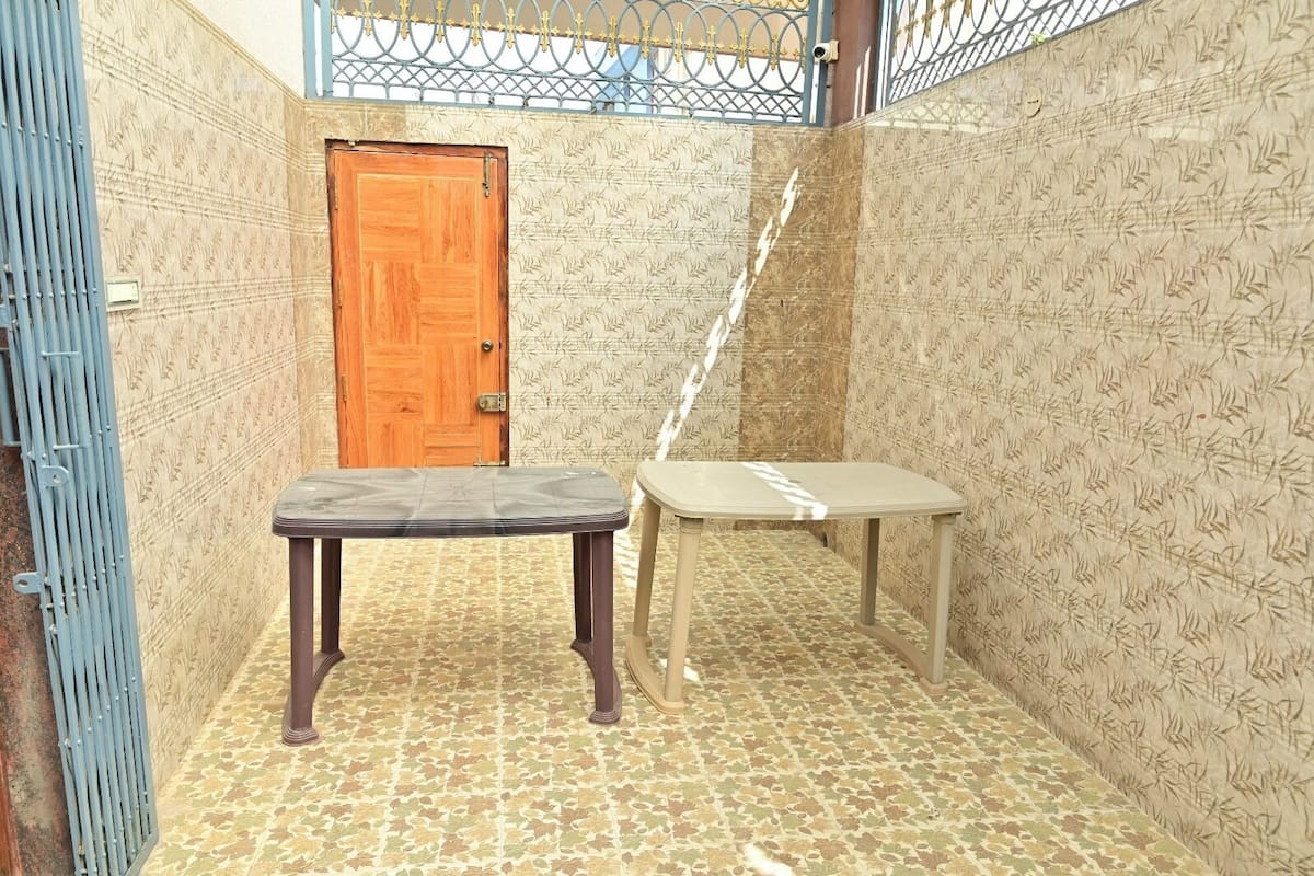Una habitación pequeña con una puerta de madera, una mesa y un papel tapiz estampado.