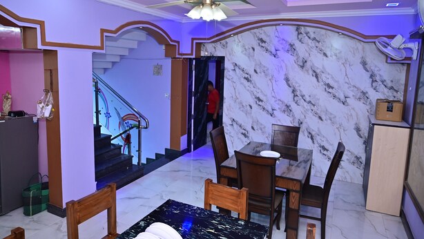 A dining area with a marble wall, a ceiling fan, and a staircase leading to another level. - Mayur Shines (Anekal)