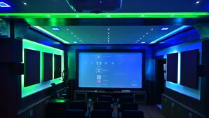 A home theater with a large screen, multiple speakers, and a row of seats. - Mayur Shines (Anekal)