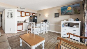 A compact living space with a kitchen, dining area, and a seating area with a TV mounted on the wall. - Ocean Forest Plaza 708 - Oceanfront (Myrtle Beach)