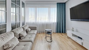 Een moderne woonkamer met een bank, een ronde tafel en een televisie op een witte muur.